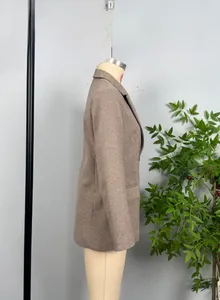 Detailed view of brown herringbone blazer fabric with classic lapel and flap pocket