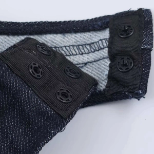Dettaglio della chiusura con bottoni a pressione su tessuto denim blu scuro del body