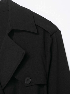 Detail der Schulterklappe und des Doppelreiher-Kragens am schwarzen Trenchcoat