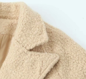Detailed macro view of beige lamb wool coat featuring a wide collar and silky inner lining