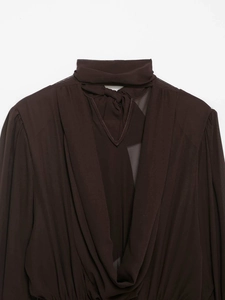 Dettaglio di abito in chiffon marrone scuro con collo alto ed elegante fiocco posteriore