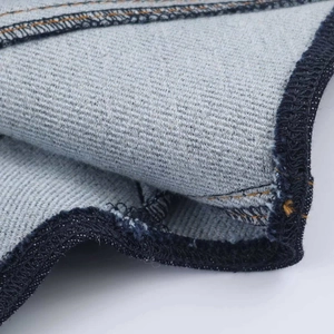 Dettaglio di tuta in denim con tessuto twill blu e cuciture arancioni a contrasto