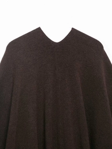 Close-up detail of dark brown V-neck knit poncho featuring thick wool texture