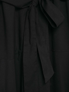 Detailansicht des gewebten Stoffes und der feinen Schleife am schwarzen Trenchcoat