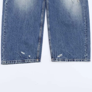 Détail du pantalon en jean à taille haute avec ourlet rétro vieilli et effet de moustache