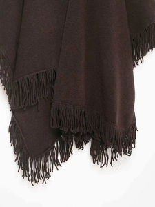 Close-up of deep brown knit poncho featuring thick wool-like texture and dense fringe trim