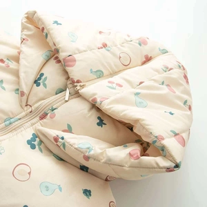 Détail d'une veste à capuche pour bébé avec motifs de fruits et fermeture éclair métallique