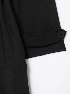 Detailansicht eines schwarzen Trenchcoat-Ärmels mit geknöpfter Manschette und Köpergewebe