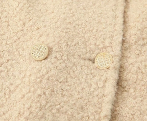 Close-up of curly sherpa fleece texture with textured golden buttons on long coat