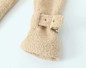 Detail shot of lamb wool coat cuff featuring a decorative strap with a gold metal buckle