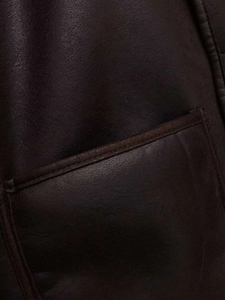 Gros plan du manteau en similicuir marron foncé montrant la texture et la poche plaquée