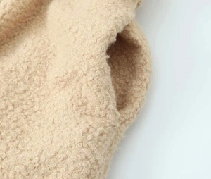 Macro shot of fluffy beige sherpa fabric texture and side pocket detail on long coat