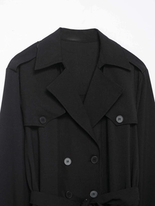 Details eines klassischen schwarzen zweireihigen Trenchcoats mit Revers und Schulterklappen