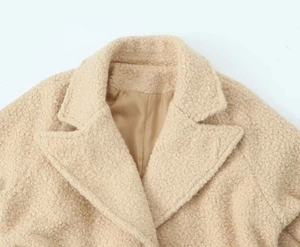 Detail shot of the plush apricot faux shearling fabric and elegant notch lapel collar