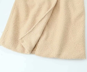 Close-up of thick beige faux shearling fabric with smooth inner lining and fine stitching