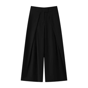 Detailed view of black pleated wide-leg trousers with a smooth draped woven fabric finish