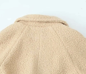 Close-up of beige fleece coat showing textured collar and neat shoulder stitching detail