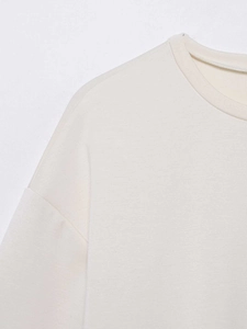 Gros plan détaillé d'un t-shirt crème ample avec col rond et coutures en dentelle