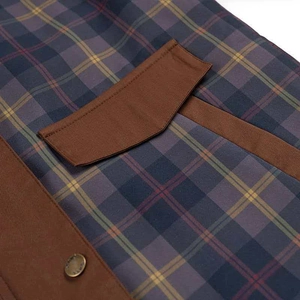 Dettaglio della giacca a quadri blu navy con tessuto a contrasto marrone e bottone in metallo