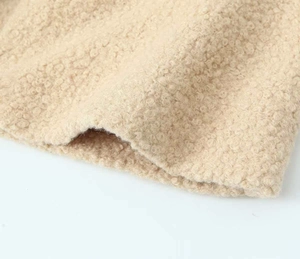 Close-up detail of soft beige sherpa fleece fabric showing premium curly wool texture