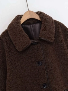 Détail de la veste en similicuir marron foncé avec passepoil en cuir et boutons