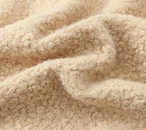 Detailed macro shot of warm beige teddy fleece fabric with soft curly fiber texture