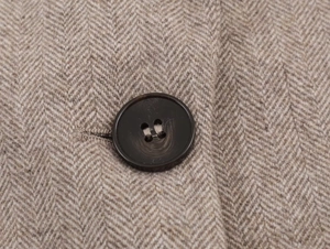 Macro shot of brown resin button on classic herringbone texture of the tweed blazer jacket