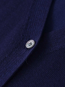 Gros plan détaillé sur la maille bleu marine et le bouton gris d'un haut à col en V