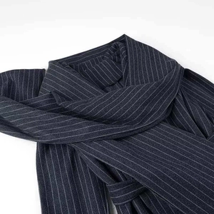 Détail d'un manteau en laine bleu marine à fines rayures avec col écharpe et texture épaisse