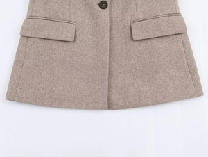 Detail of herringbone wool blazer showing dual flap pockets and a single brown button