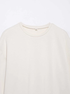 Gros plan du col rond d'un t-shirt crème avec bords côtelés et étiquette de taille S
