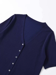 Détail du cardigan en maille bleu marine avec col en V et petits boutons blancs
