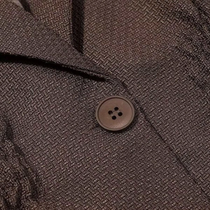 Detail of dark brown blazer featuring textured tweed fabric and matching round button