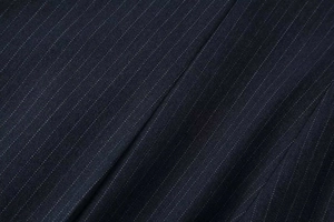 Macro detail of dark blue pinstripe fabric texture on wide-leg fashion trousers