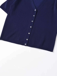 Détail du cardigan bleu marine à col en V montrant les boutons blancs et la maille