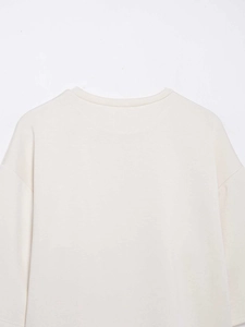 Vue détaillée du haut beige à manches longues montrant les coutures du col et la texture