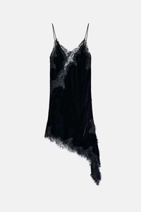 Detail of delicate eyelash lace trim and velvet texture on black asymmetric slip dress