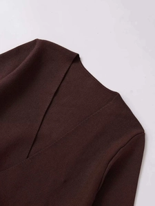 Détail d'un pull en tricot marron foncé avec col en V montrant la texture du tissu