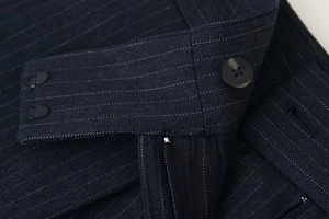 Detailed macro view of dark blue pinstripe wide-leg trousers featuring a secure waist closure