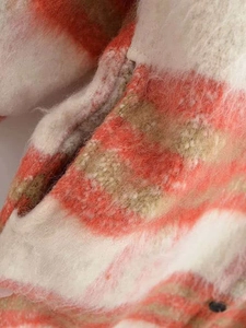 Dettaglio del morbido tessuto scozzese spazzolato arancio e kaki con cuciture sulla tasca