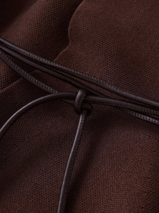 Détail macro du tricot marron foncé avec lacet en cuir et coutures de précision