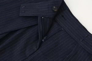 Detailed macro view showing zipper, hook-and-eye closure on navy blue striped trousers