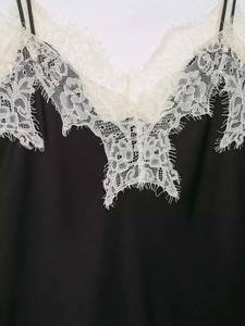 Détail de la dentelle blanche sur le haut en satin noir avec de fines bretelles