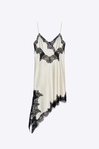 Detailed view of cream silk dress with black eyelash lace trim and asymmetric hem