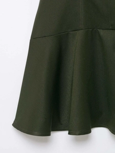 Detailed close-up of dark green dress showing twill fabric and ruffle hemline seams