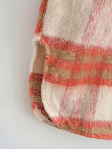 Dettaglio della giacca a camicia a quadri rossa e kaki con texture morbida e spacco laterale