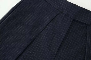Close-up of dark blue herringbone fabric with fine white stripes and pleated detailing