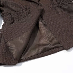 Detailed close-up of brown tweed blazer featuring textured fabric and smooth satin lining