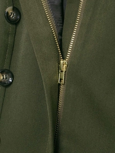 Detail of army green twill fabric with golden metal zipper and marble pattern button
