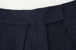 Detail view of navy blue wide-leg trousers featuring white pinstripes and herringbone texture